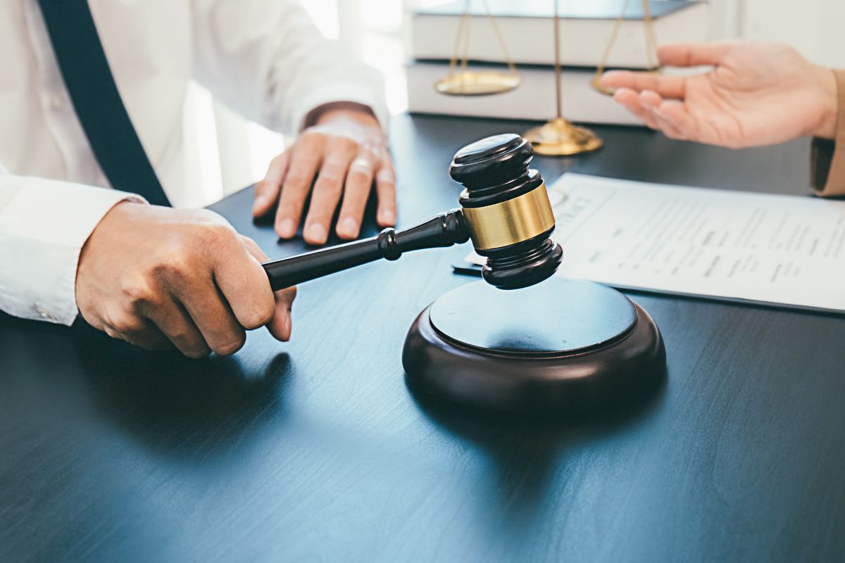 Judge with gavel near legal documents and scales of justice.