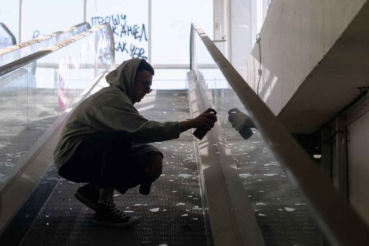 Man spray painting graffiti in a public space.