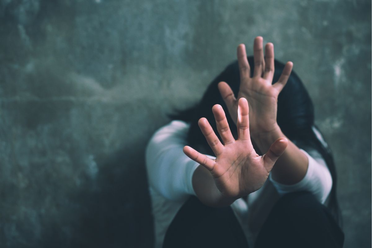 Scared woman raising her hands in self-defense against a threat.