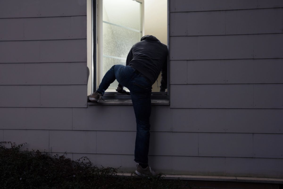 Person climbing through a house window.