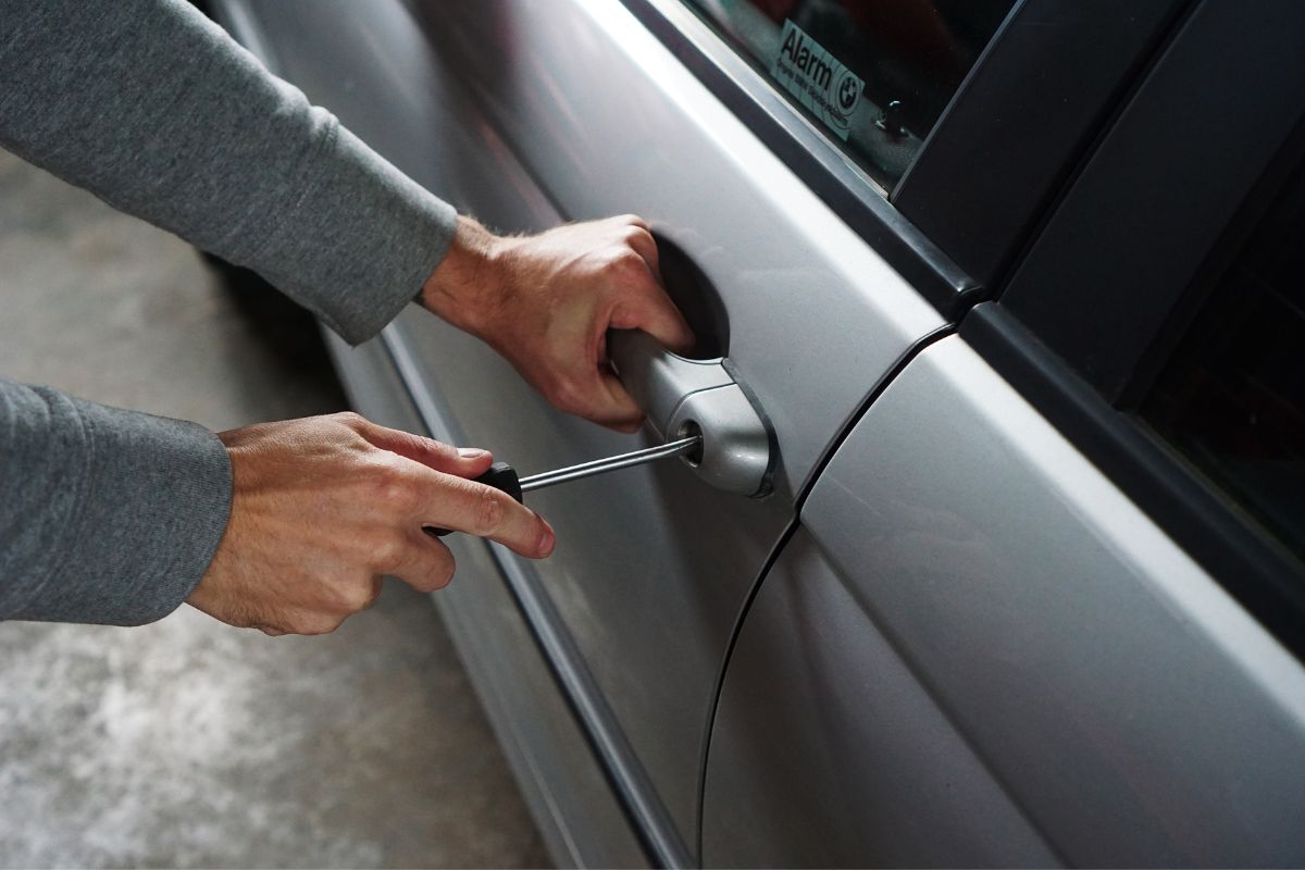 Person using a screwdriver to break into a car door.