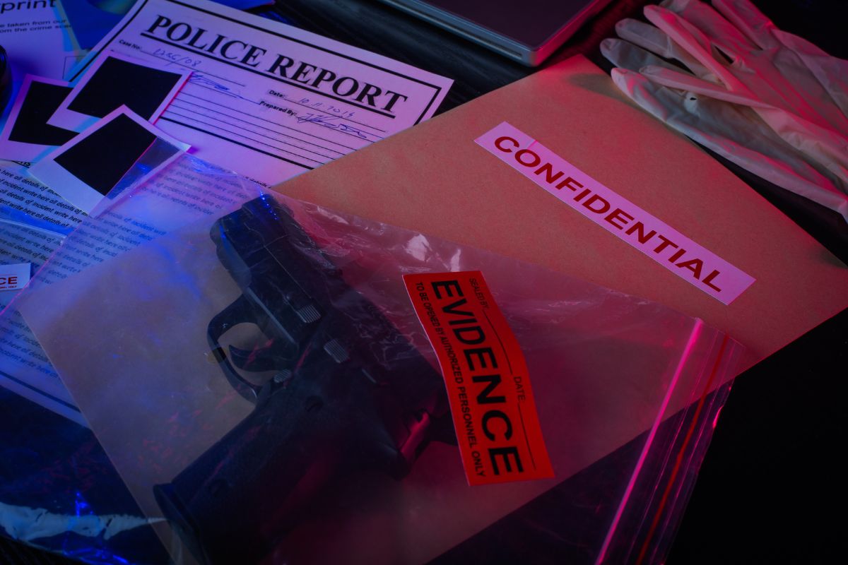 Evidence bag containing a handgun on top of a police report and confidential file.