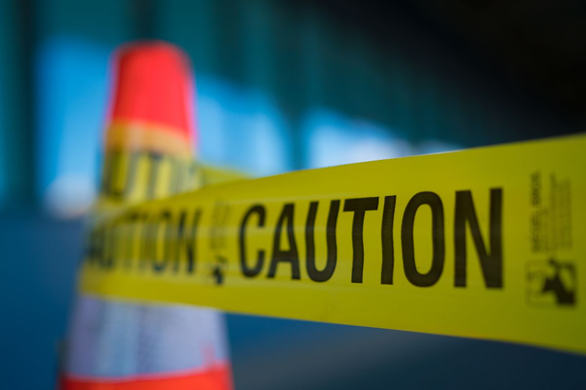 Police caution tape with a traffic cone.