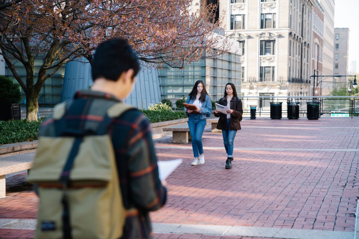Student skipping class while others walk on school campus.