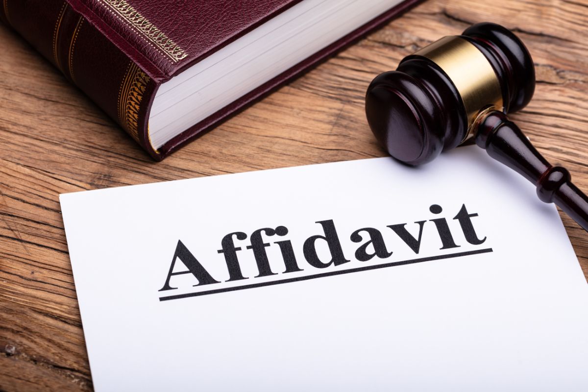 A paper labeled “Affidavit” next to a gavel and a law book on a desk.
