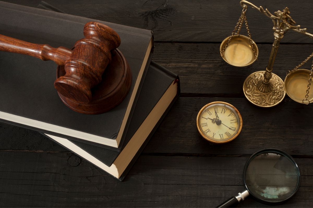 A judge's gavel, legal books, a vintage clock, and a golden balance scale.