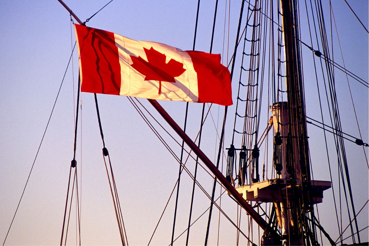 The Canadian flag is flying on the mast of a ship.
