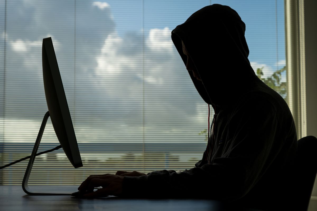 A person in a hoodie is using a computer in an online obscenity crime.