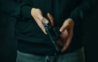 A man holding a revolver with the cylinder open.