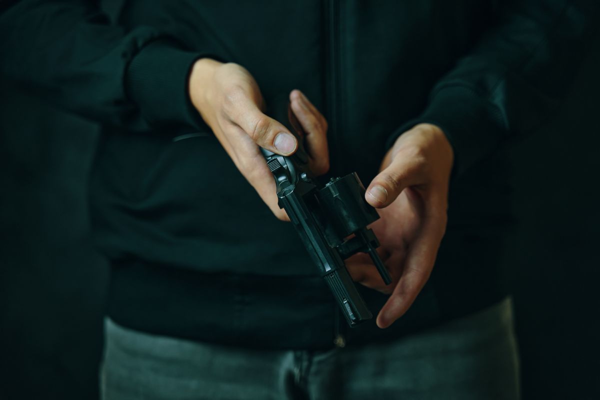 A man holding a revolver with the cylinder open.
