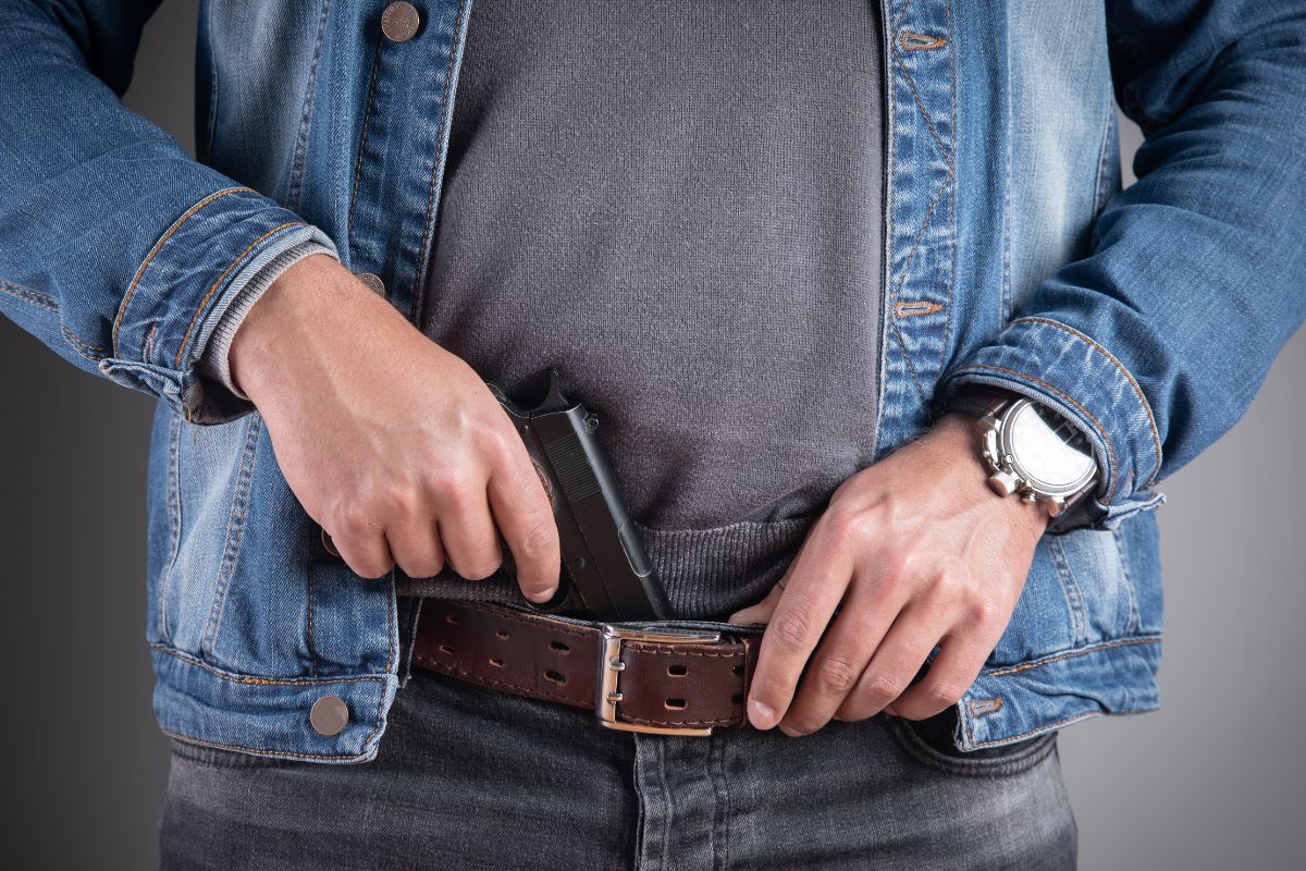 A man tucks a handgun.