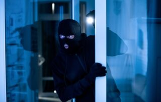Masked burglar entering a building.