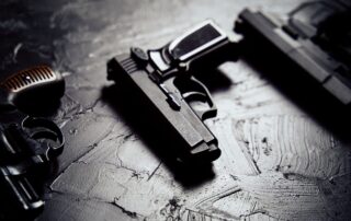 Multiple handguns are placed on a dark textured surface.