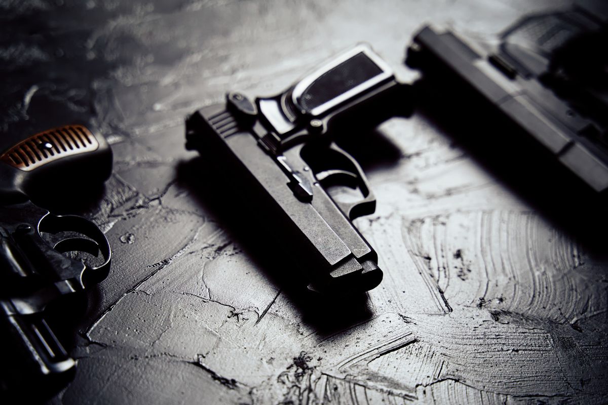 Multiple handguns are placed on a dark textured surface.