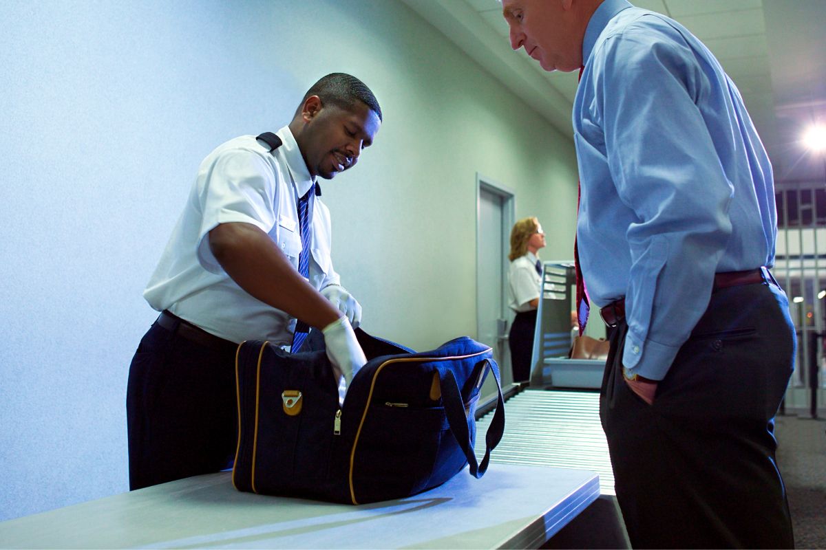 Border officer checking a traveler’s bag. Border officer checking a traveler’s bag.