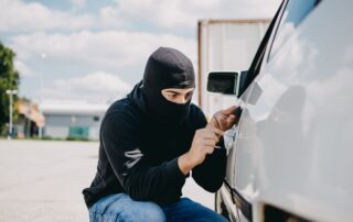 Masked person attempting car theft.