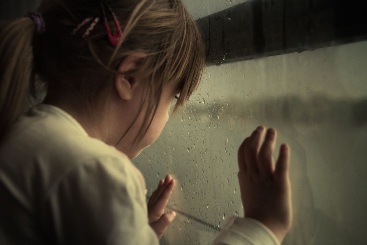 A young child looking out of a window. A young child looking out of a window.