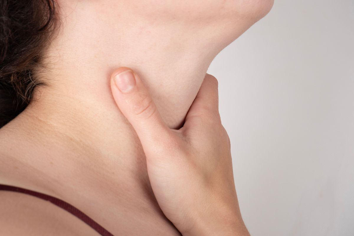 A close-up of a person holding their neck. A close-up of a person holding their neck.