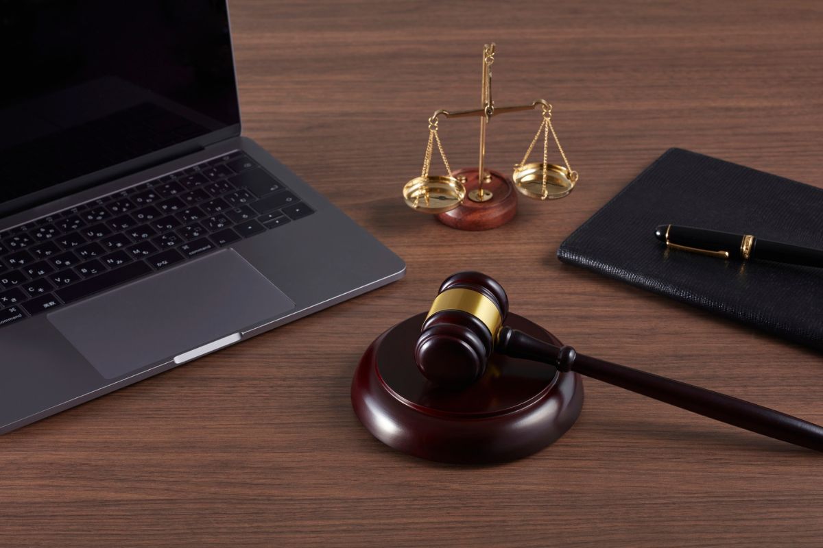 A gavel, laptop, and scales of justice on a lawyer’s desk. A gavel, laptop, and scales of justice on a lawyer’s desk.
