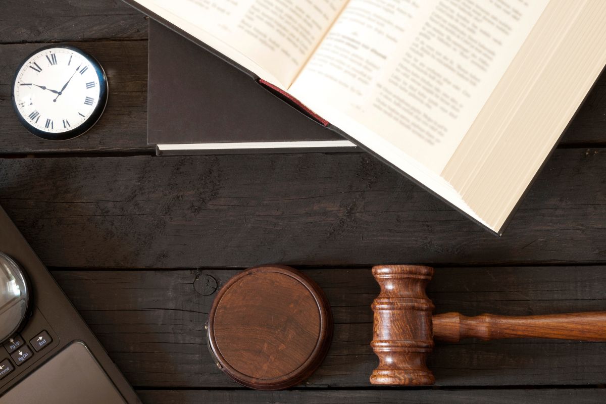 Open law book, gavel, and pocket watch. Open law book, gavel, and pocket watch.