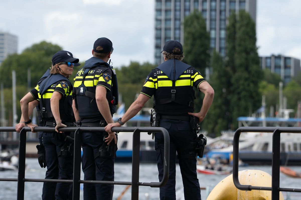 Three police officers standing near a railing by the water.