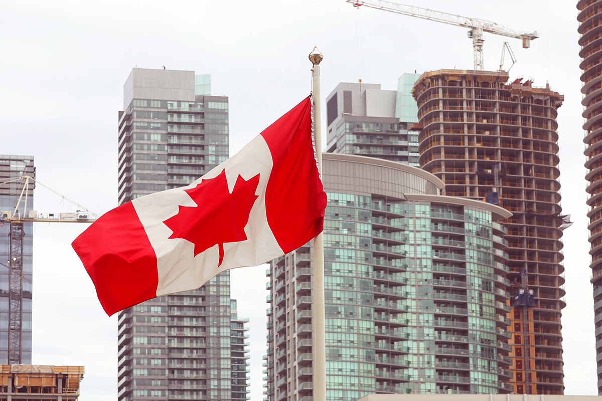 A Canadian flag flies in front of a city skyline.