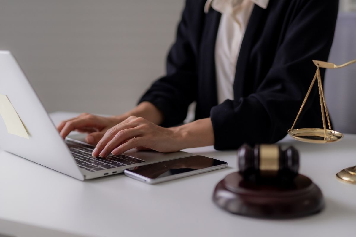 Lawyer working on a laptop with a gavel and scales of justice on the desk. Lawyer working on a laptop with a gavel and scales of justice on the desk.