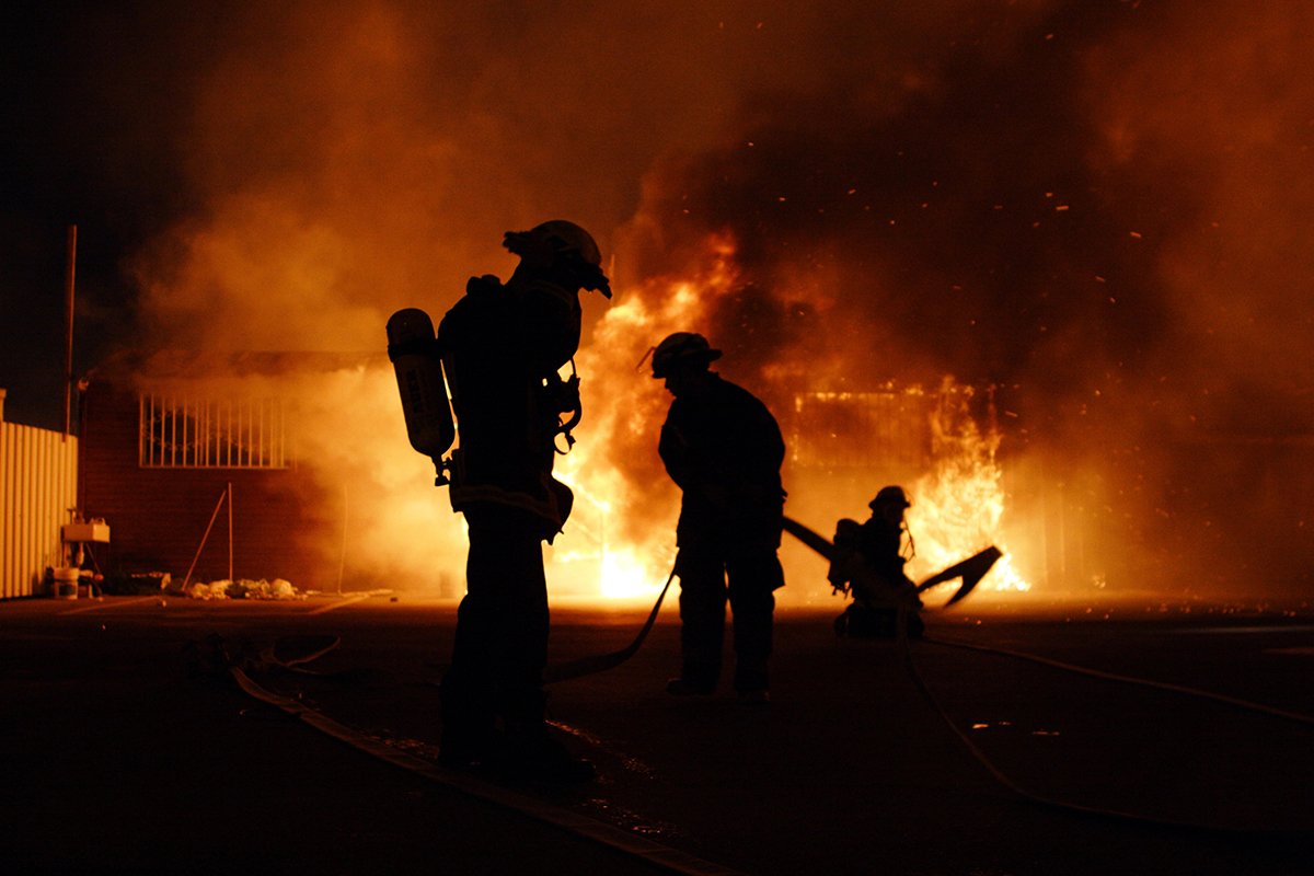 Fire fighters standing in front of a burning building
