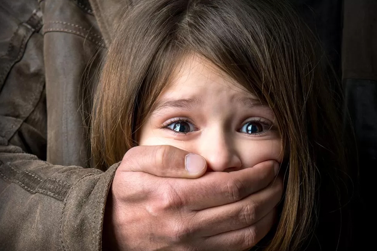 A young girl with a hand over her mouth