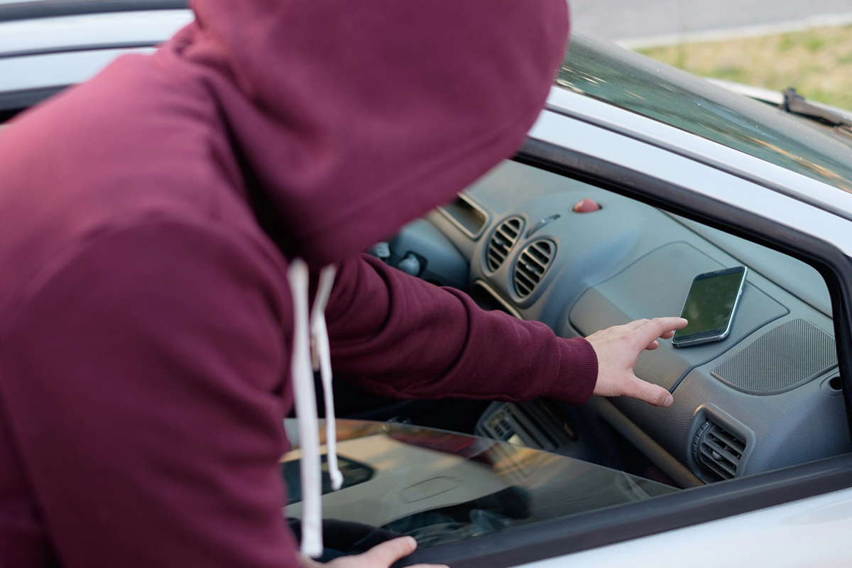 A person reaches for a cell phone on a car dashboard