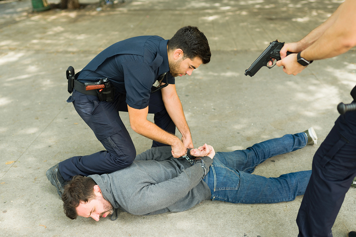 A young man resists arrest by police officers