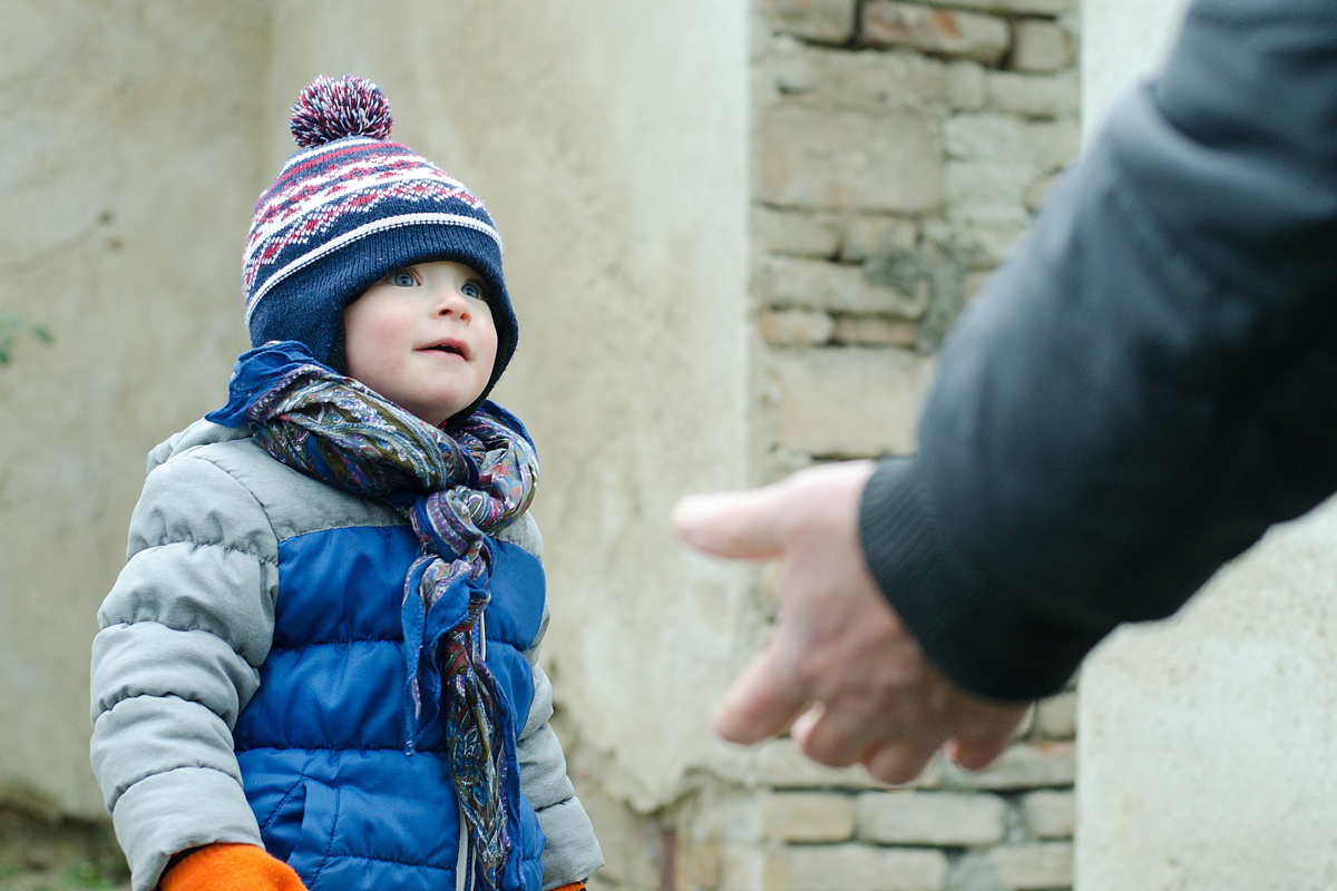 A person reaches a hand toward a child.