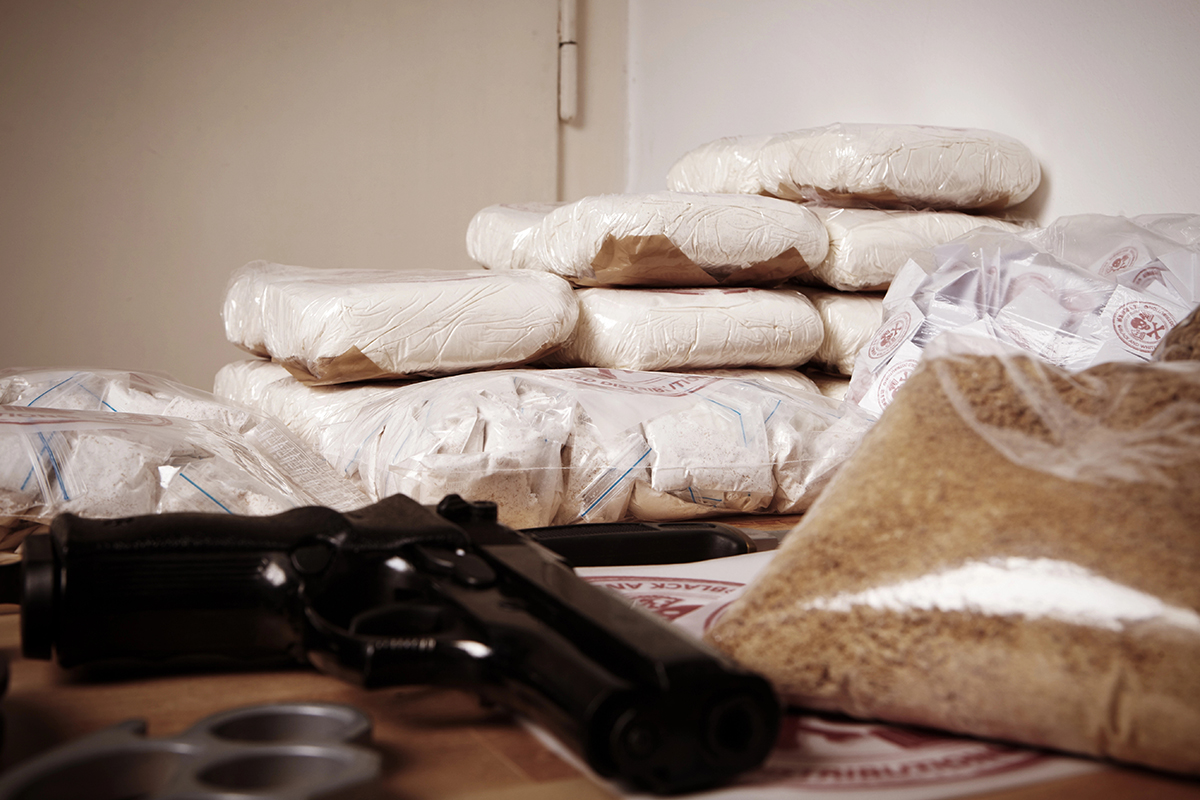 A table with illegal drugs and a firearm