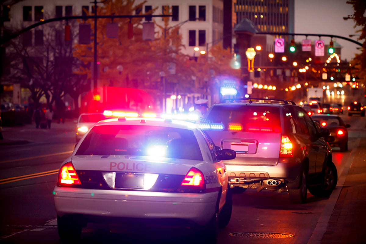 A police car with flashing lights with a vehicle pulled over