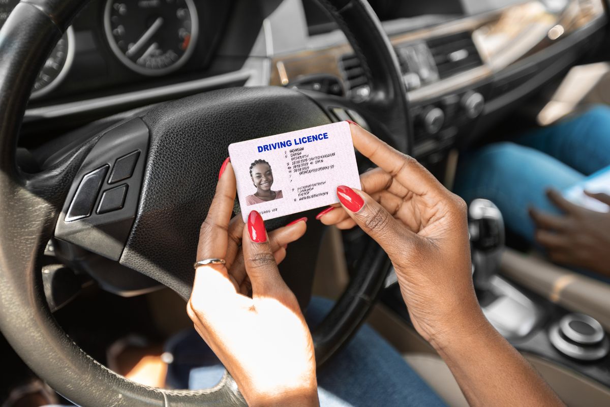 Person holding a driver's license inside a car.