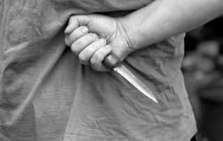A person holding a knife behind their back.