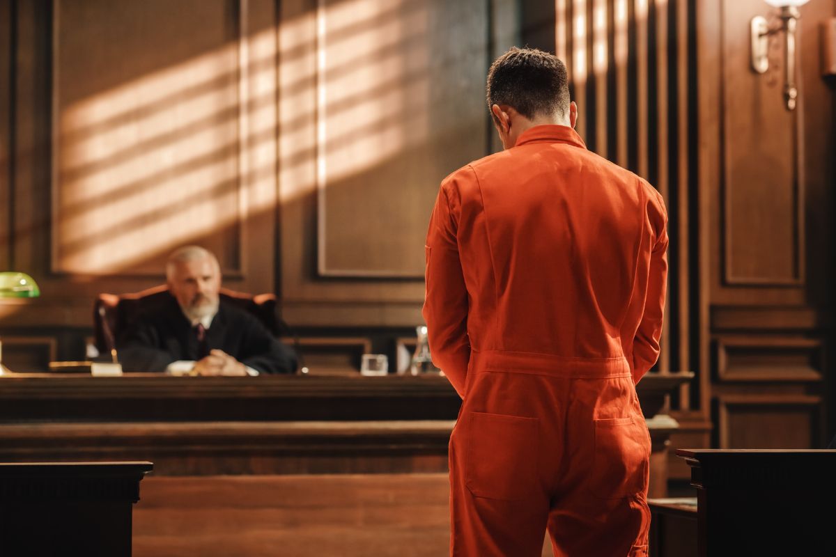 Defendant standing before a judge in a courtroom.