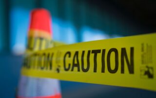 Police caution tape with a traffic cone.