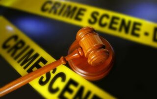 Judge’s gavel placed in front of yellow crime scene tape.