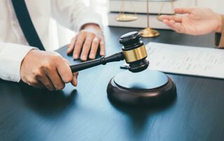 Judge with gavel near legal documents and scales of justice.