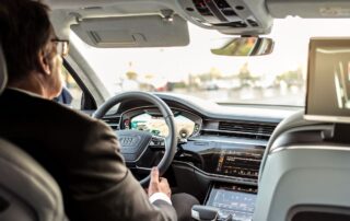 A man in a suit driving an Audi vehicle.