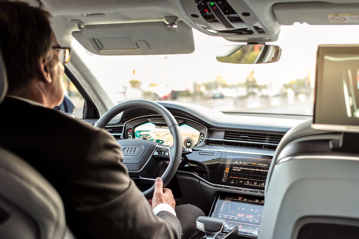 A man in a suit driving an Audi vehicle. A man in a suit driving an Audi vehicle.