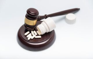 Judge’s gavel next to an open pill bottle and scattered capsules