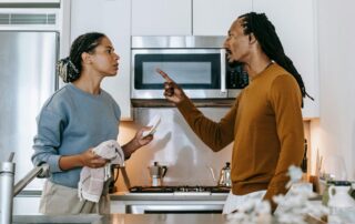 Annoyed man threatening his girlfriend during a conflict in the kitchen.