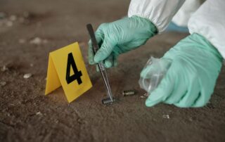 Investigator collecting bullet casing evidence at a crime scene.