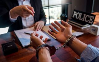 Criminal defence lawyer consulting a handcuffed man inside a police station.