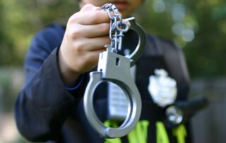 A law enforcement officer holding a pair of handcuffs.
