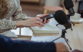 Journalist taking notes with a phone and notebook during an interview.