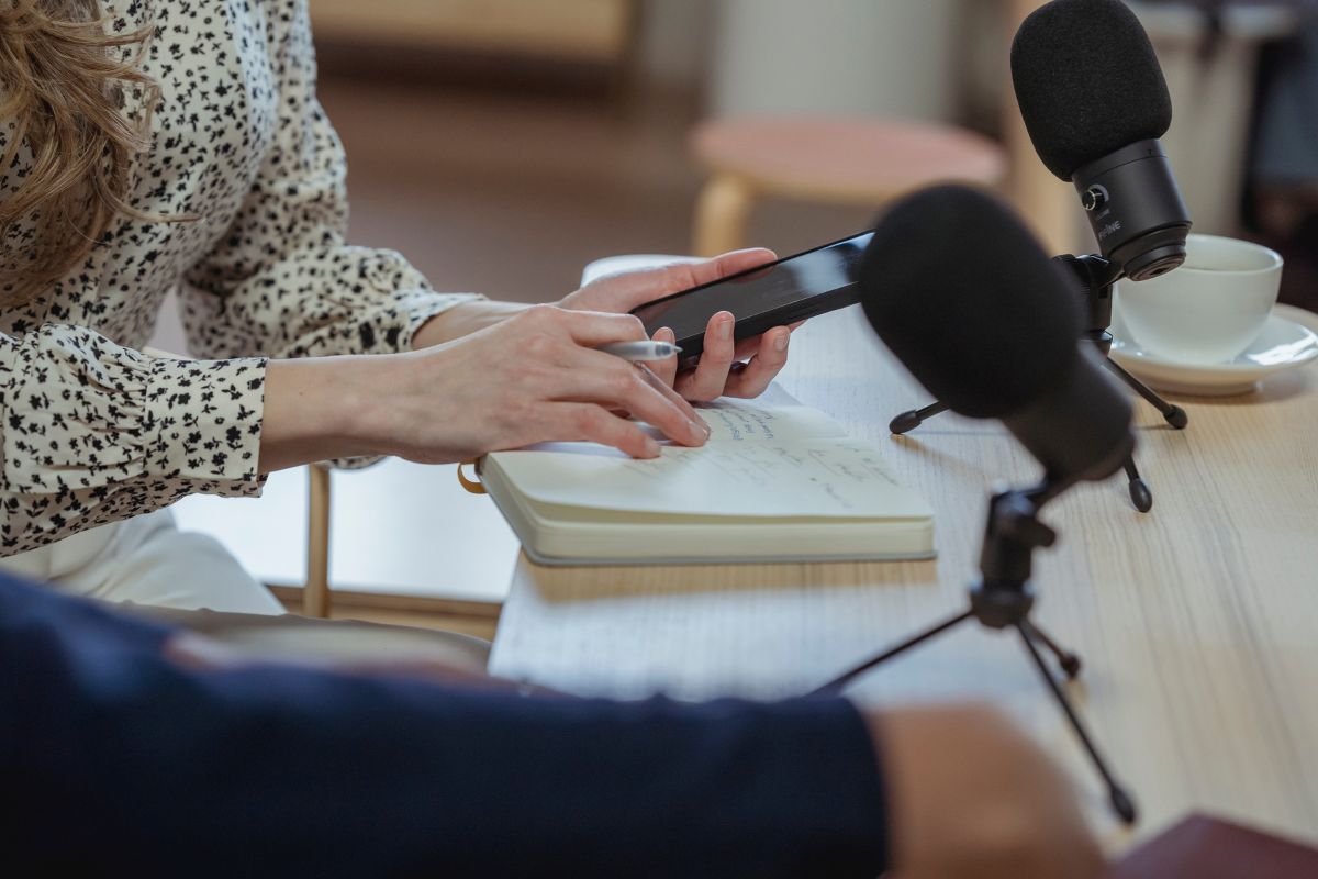 Journalist taking notes with a phone and notebook during an interview. Journalist taking notes with a phone and notebook during an interview.
