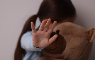 Scared child holding a teddy bear.